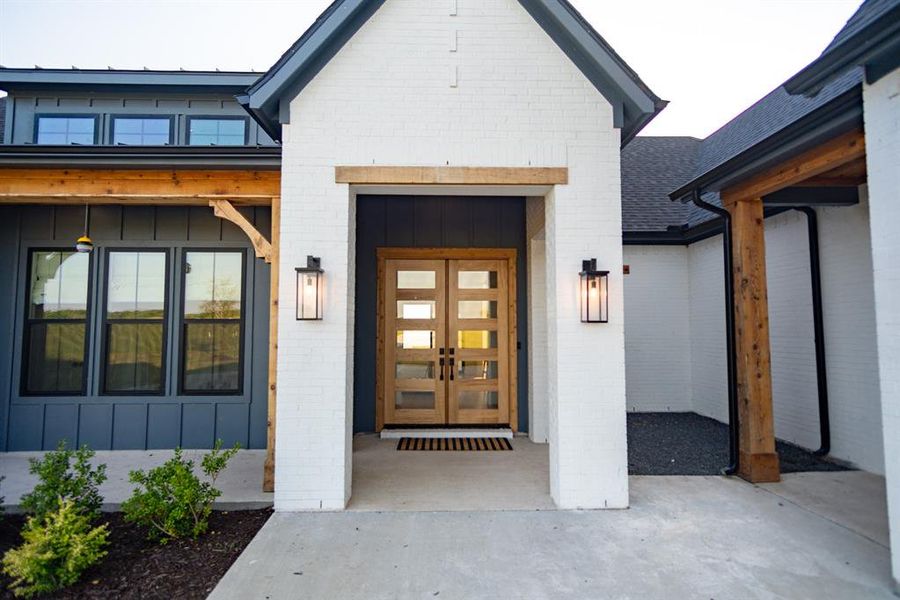 Property entrance with board and batten siding, brick siding, and french doors Property entrance with board and batten siding, brick siding, and french doors