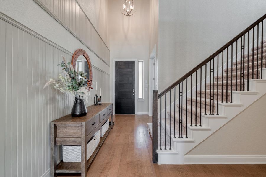 A soaring foyer, detailed wall paneling, and statement lighting set the tone.