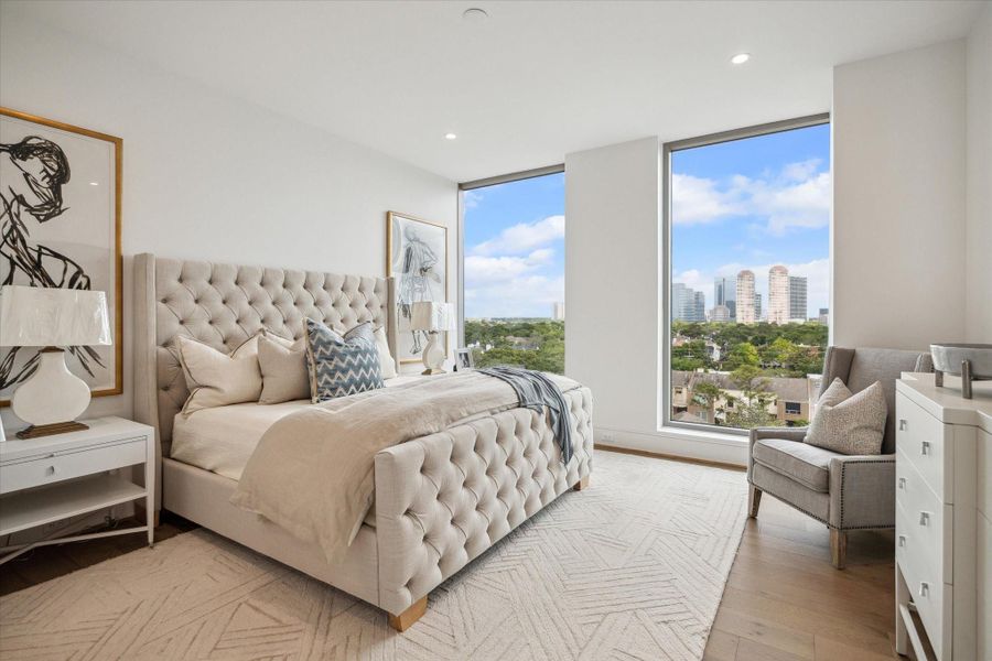 Wake up to stunning Eastern sunrises in this primary bedroom, complete with sprawling walls of windows and convenient motorized shades. Photo of a similar unit with same layout