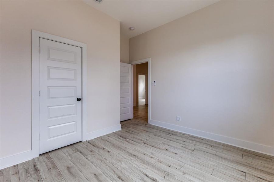 Unfurnished bedroom featuring light wood finished floors and baseboards