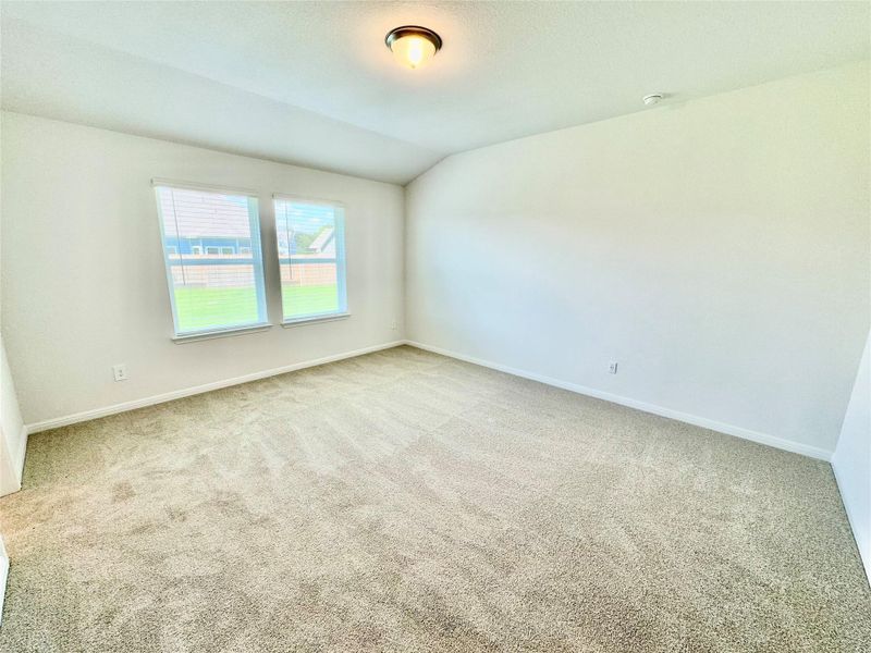 Carpeted empty room with vaulted ceiling and baseboards Carpeted empty room with vaulted ceiling and baseboards