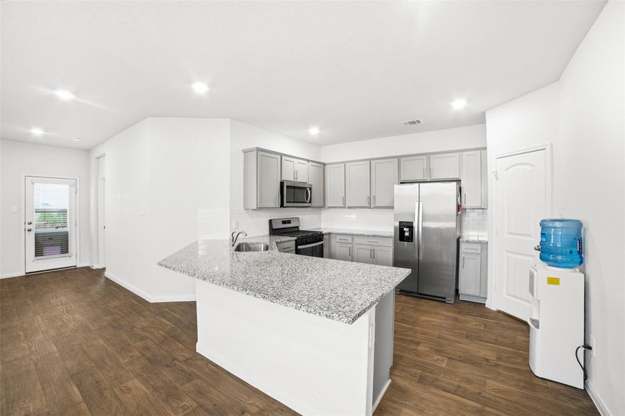 Kitchen with gray cabinets, a peninsula, stainless steel appliances, dark wood-style floors, and recessed lighting Kitchen with gray cabinets, a peninsula, stainless steel appliances, dark wood-style floors, and recessed lighting