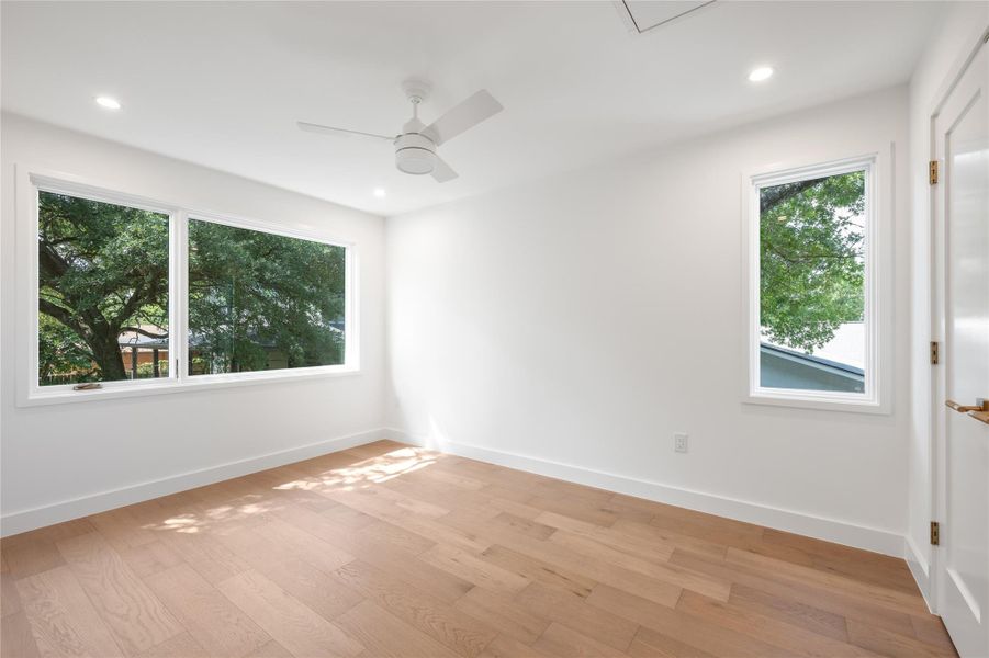 Hardwood floors and a ceiling fan create a comfortable atmosphere in this sun-filled bedroom. Hardwood floors and a ceiling fan create a comfortable atmosphere in this sun-filled bedroom.