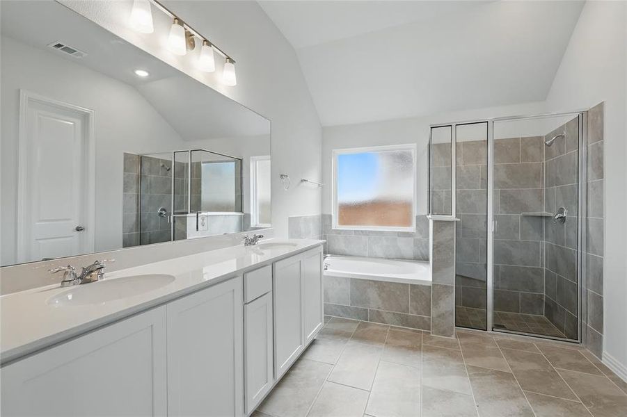 Bathroom with vaulted ceiling, double vanity, a stall shower, a bath, and light tile patterned flooring