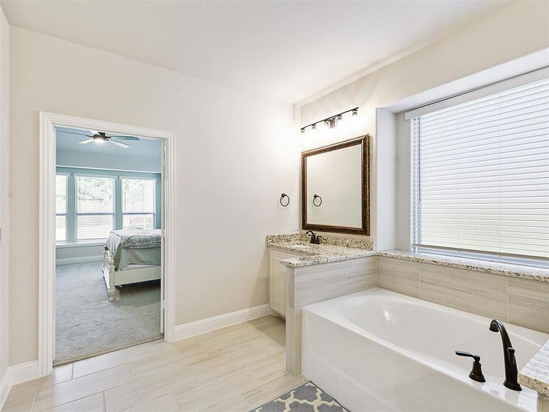 Primary Bathroom with vanity, a bathtub, and ceiling fan