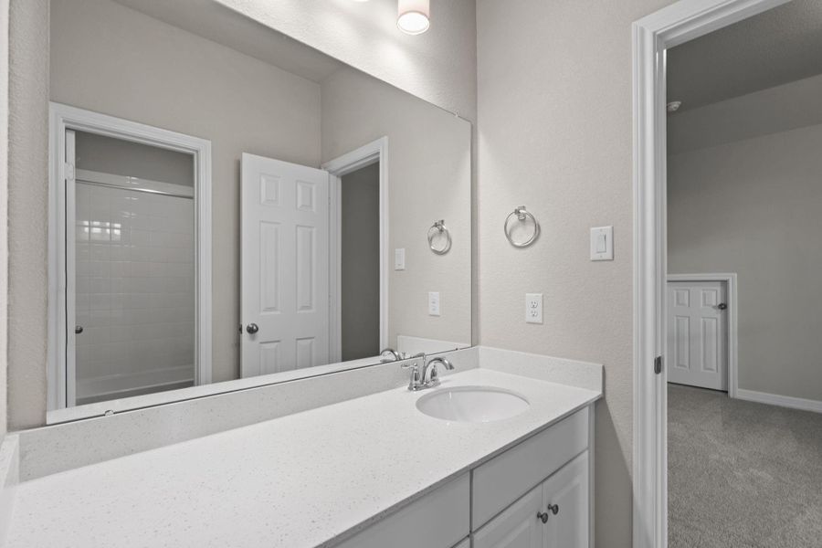 The secondary bath features tile flooring, white cabinetry and light countertops and a shower/tub combo. Perfect for accommodating any visiting family and friends.