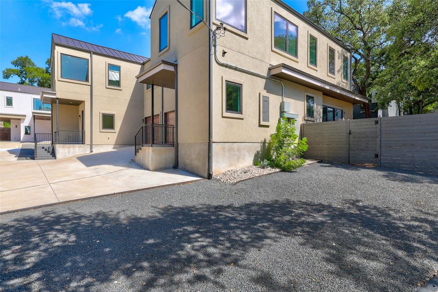 View of property exterior featuring a standing seam roof, a metal roof, stucco siding, and a gate