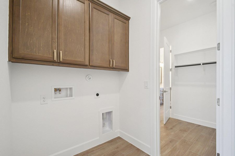 Washroom with light wood-style floors, washer hookup, cabinet space, and electric dryer hookup