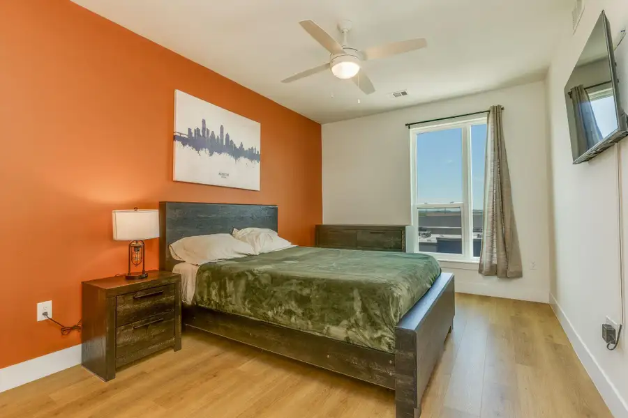 This bedroom features a ceiling fan, a window with a view, and light-toned flooring