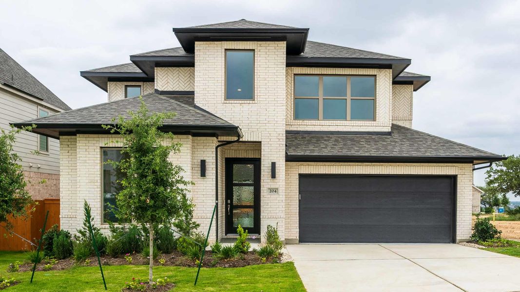 Prairie-style home featuring brick siding, a shingled roof, and an attached garage Prairie-style home featuring brick siding, a shingled roof, and an attached garage