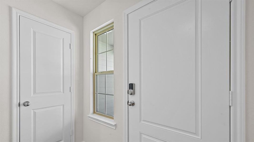 Entryway featuring a paneled door with smart lock hardware, a secondary paneled door, and a multi-pane window with a light-colored frame