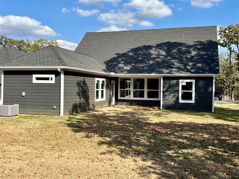 Back of house featuring a yard and central air condition unit