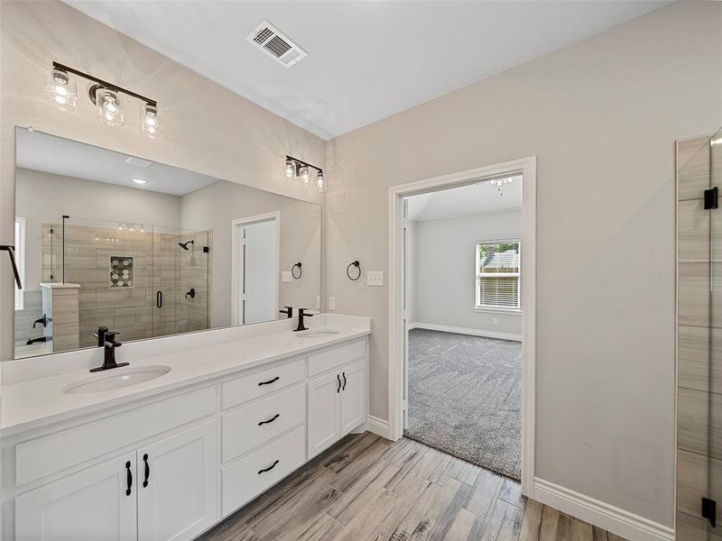 Bathroom featuring a shower stall, light wood-style flooring, and double vanity Bathroom featuring a shower stall, light wood-style flooring, and double vanity