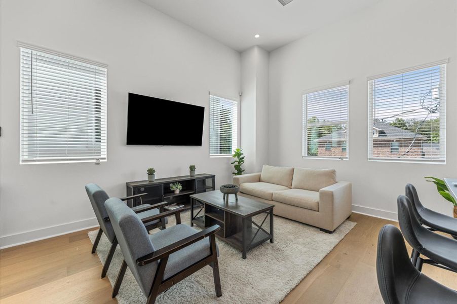 The living area, part of a bright open-concept living, dining, and kitchen on the second floor, offers plenty of space while maintaining its own personality, surrounded by windows that fill the room with natural light and create a welcoming, airy atmosphere perfect for relaxing or entertaining.