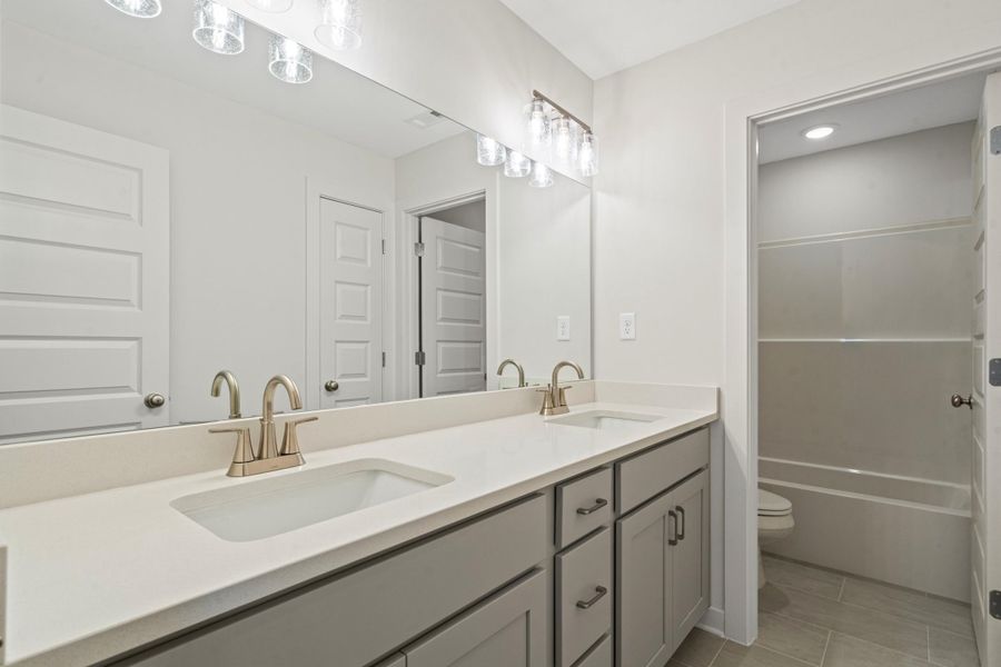 Double vanity featuring light gray cabinetry, brushed nickel fixtures, and a white countertop Double vanity featuring light gray cabinetry, brushed nickel fixtures, and a white countertop