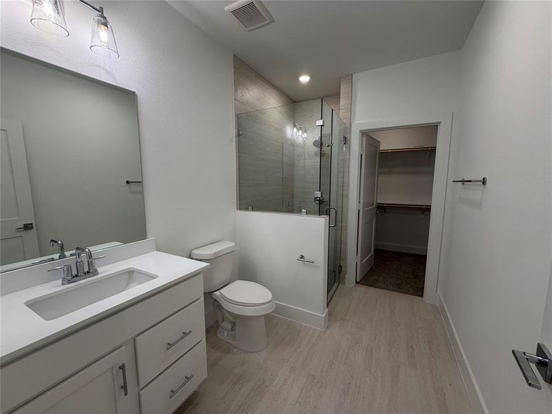 Full bath with vanity, light wood finished floors, a walk in closet, a shower stall, and recessed lighting