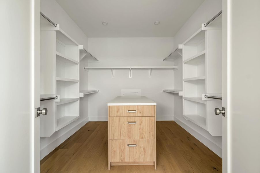 Streamlined storage solutions and a central dresser elevate this walk-in closet. Streamlined storage solutions and a central dresser elevate this walk-in closet.