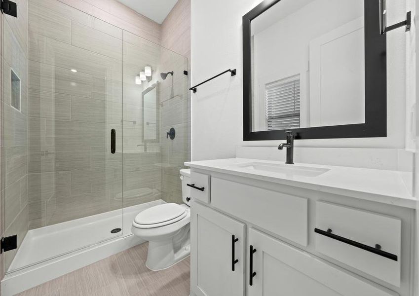 The secondary bathroom has a large vanity with plenty of cabinet space and a glass, walk-in shower.