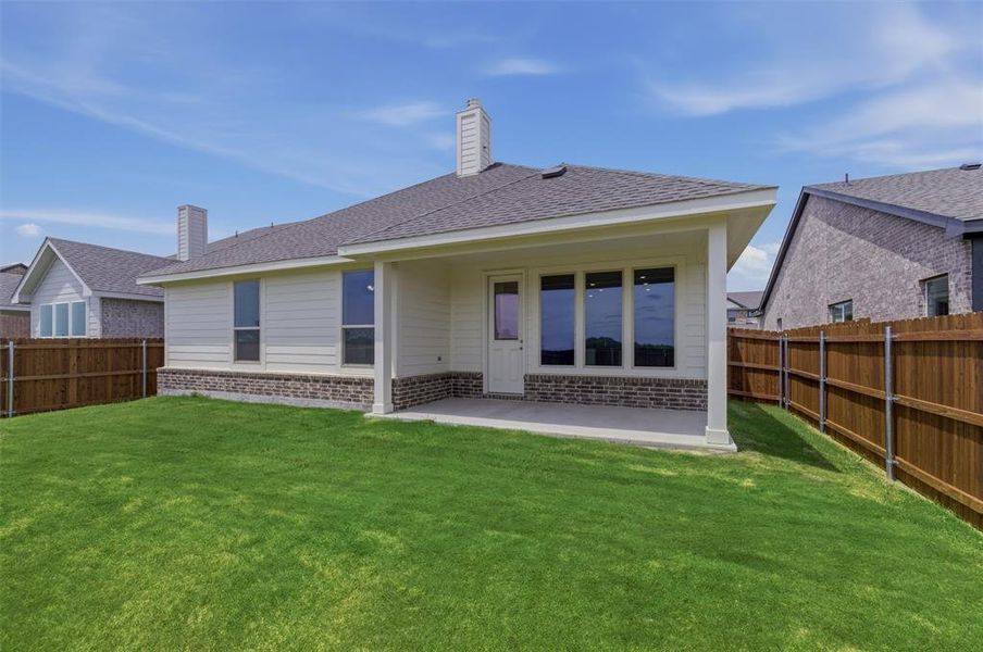 Spacious backyard featuring a covered patio, manicured lawn, and privacy fencing