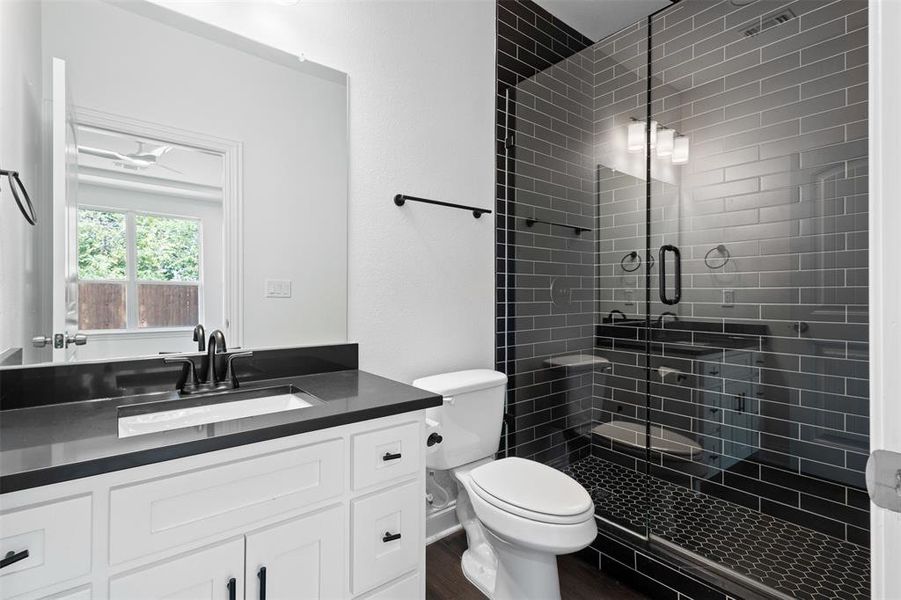 Full bathroom with vanity, a stall shower, and dark wood-style floors