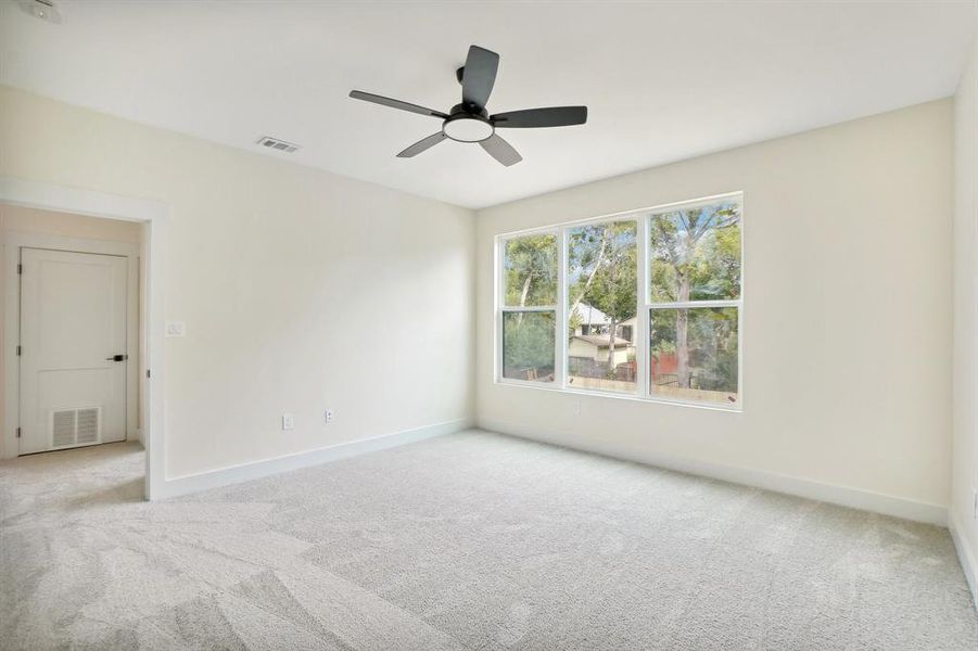 Carpeted empty room featuring ceiling fan