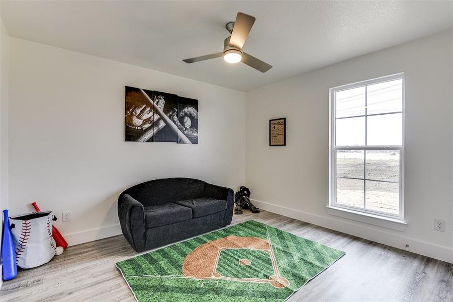 Living area with ceiling fan, plenty of natural light, wood finished floors, and baseboards