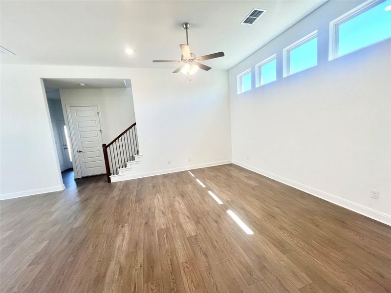 Unfurnished room featuring wood finished floors, a ceiling fan, and stairs