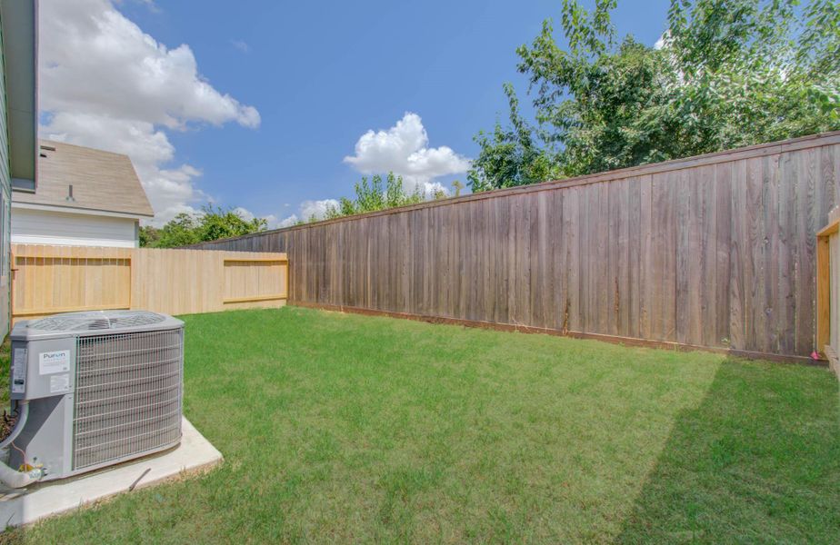 Charming backyard with lush green lawn and a wooden privacy fence, perfect for outdoor relaxation and activities.