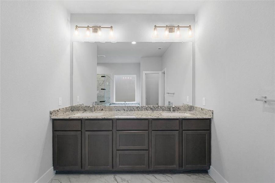 This primary bathroom is definitely move-in ready! Featuring stained cabinets with granite countertops, spacious walk-in closet with shelving, high ceilings, custom paint, sleek and dark modern finishes.