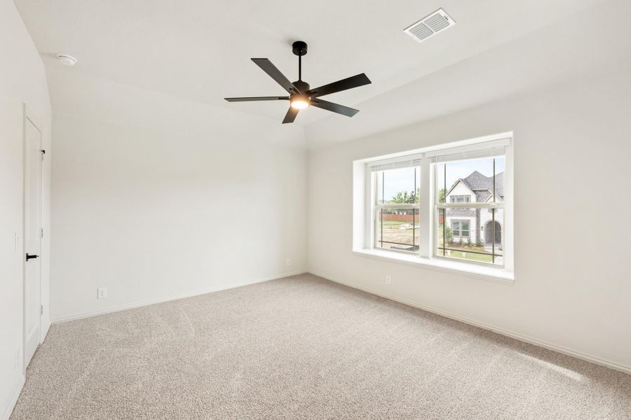 Empty bedroom with carpet flooring, black ceiling fan, and large window with neighborhood view Empty bedroom with carpet flooring, black ceiling fan, and large window with neighborhood view