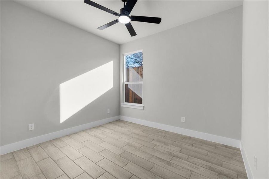 Unfurnished room with light wood-style floors, ceiling fan, and baseboards