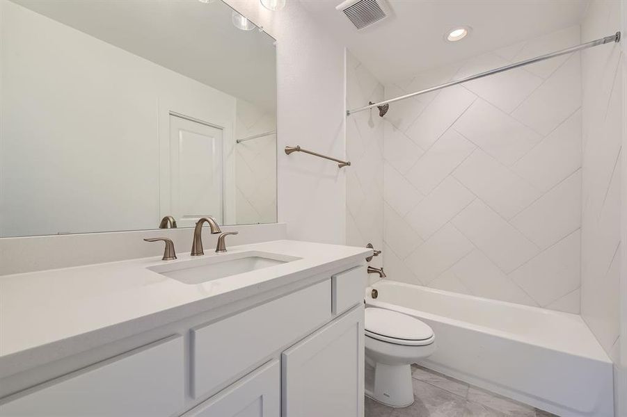 Full bathroom featuring vanity, toilet, and tiled shower / bath combo