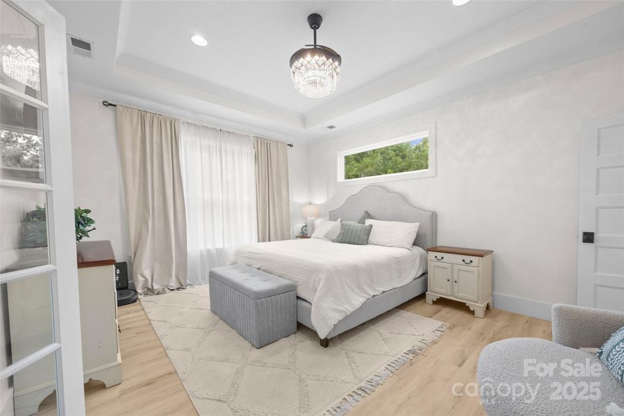primary bedroom with celestial window and tray ceiling