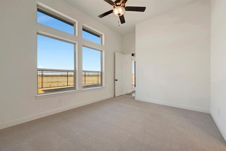 Spare room featuring ceiling fan, light carpet, and a high ceiling Spare room featuring ceiling fan, light carpet, and a high ceiling