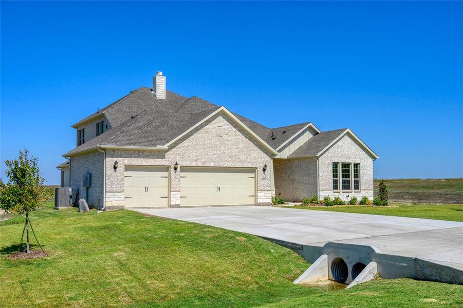 View of front of house with a garage, cooling unit, and a front yard