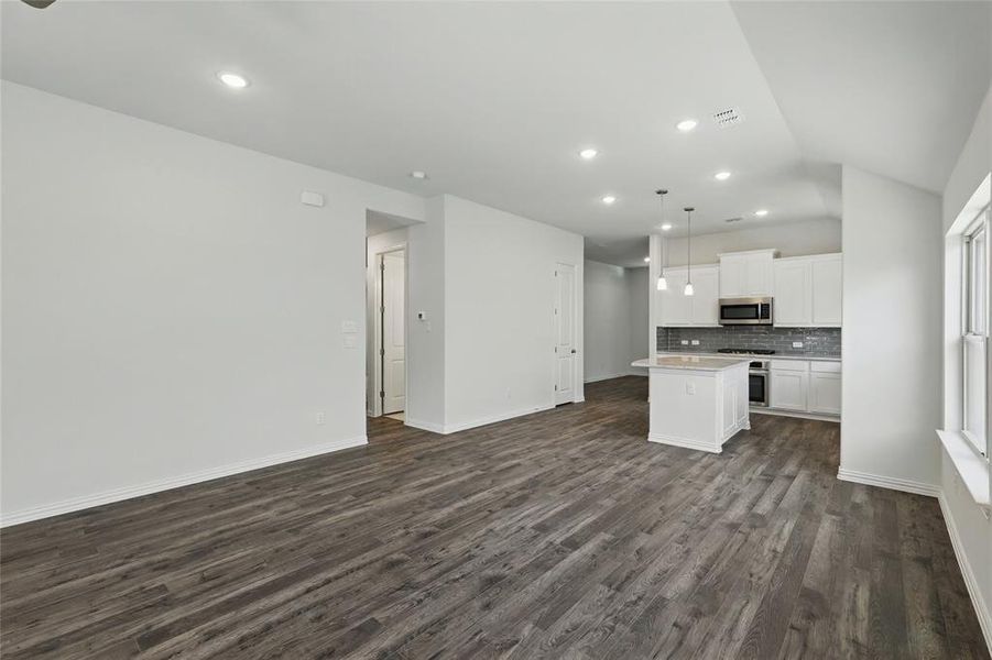 Kitchen featuring range, dark wood-style floors, stainless steel microwave, open floor plan, and backsplash