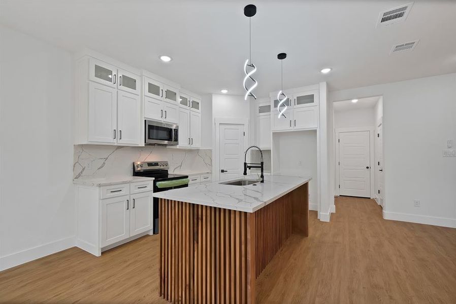 Kitchen with glass insert cabinets, appliances with stainless steel finishes, white cabinetry, light stone counters, and tasteful backsplash