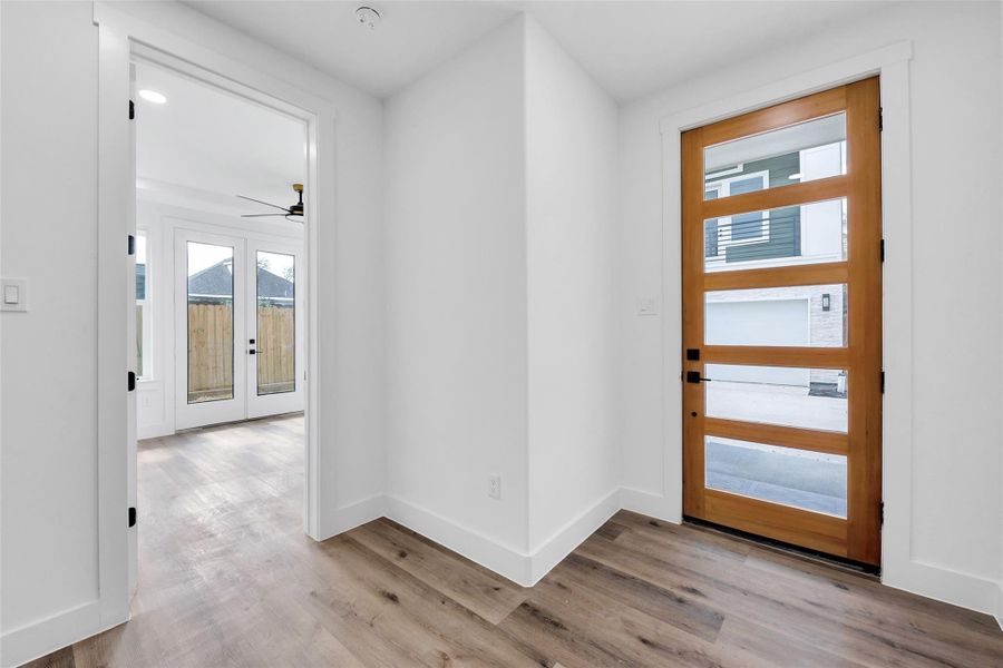 The modern door and entryway leads to a spacious foyer. The door to the left leads to one of three bedrooms with an ensuite bath.