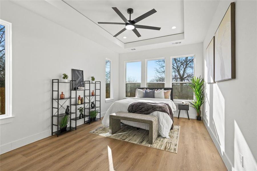 Bedroom featuring light wood-style floors, a ceiling fan, recessed lighting, and a tray ceiling