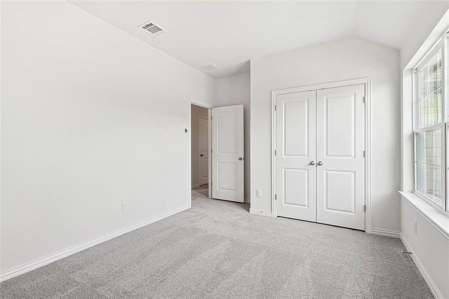 Unfurnished bedroom with a closet, vaulted ceiling, and light colored carpet