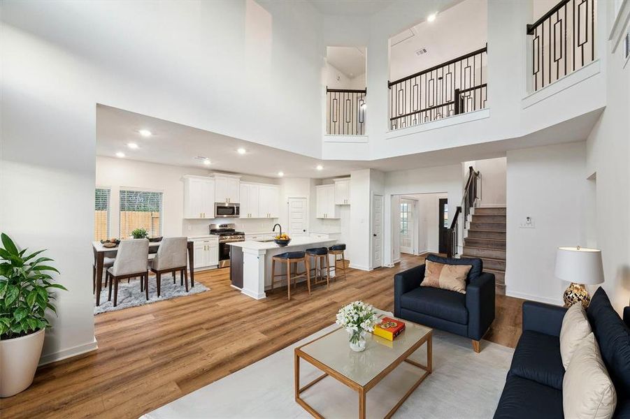 This view showcases the seamless blend of function and style in the home’s main living area. The two-story living room, complete with a modern railing and open balcony, connects to the bright kitchen and dining area. The layout is designed to accommodate both everyday living and special occasions, ensuring you’ll enjoy this space for years to come.