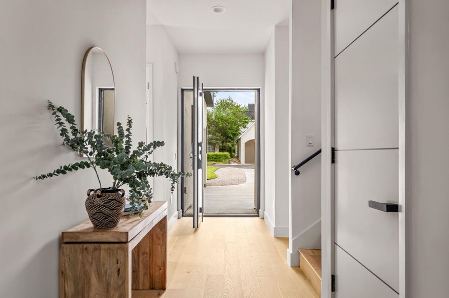 Enter into a light-filled hallway boasting gleaming hardwood floors and a clear view of the well-manicured outdoor space. Enter into a light-filled hallway boasting gleaming hardwood floors and a clear view of the well-manicured outdoor space.