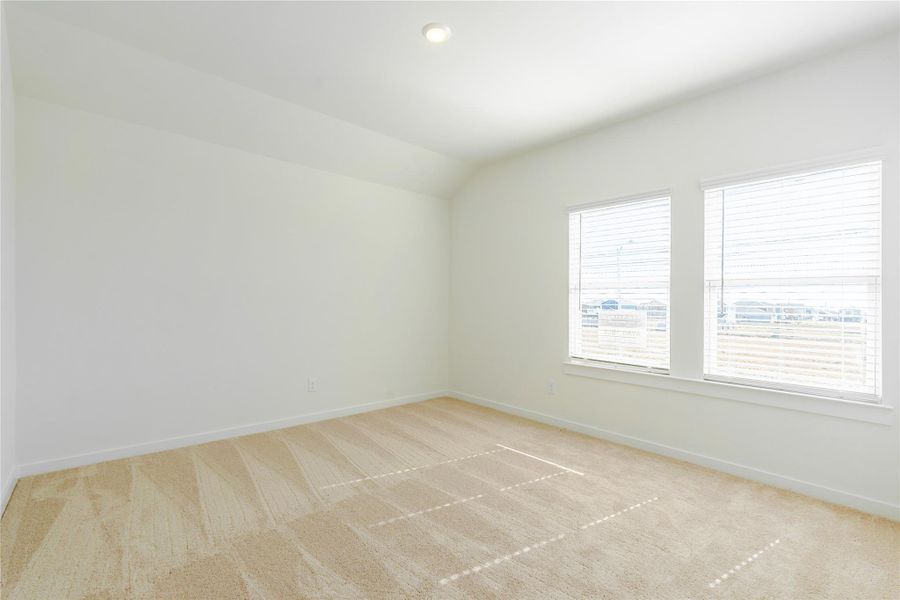 This photo shows a bright, spacious room with neutral walls and carpet, featuring two large windows that let in plenty of natural light. Perfect for a bedroom or office.