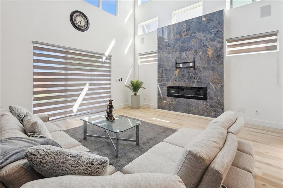 Living room featuring a fireplace, a wealth of natural light, hardwood / wood-style flooring, and a towering ceiling