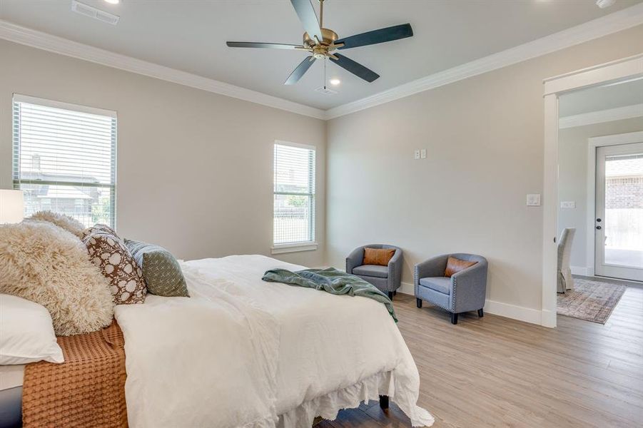 Spacious room featuring wood-finish flooring, two windows with blinds, a ceiling fan with integrated lighting, recessed lighting, and crown molding