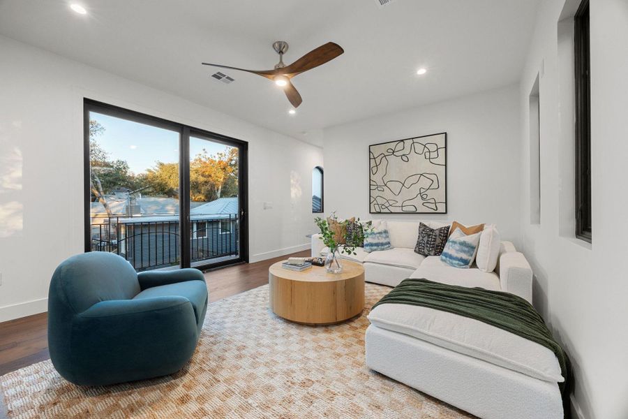 Living area with dark wood-finish flooring, white walls, and a ceiling fan