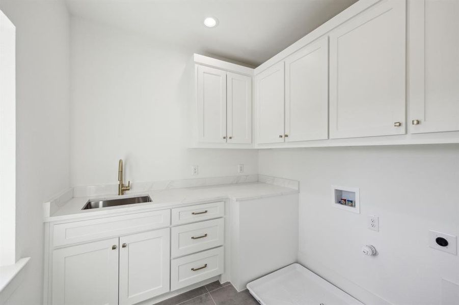 Upstairs Laundry room with electric dryer hookup, dark tile patterned flooring, washer hookup, a sink, and cabinet space Upstairs Laundry room with electric dryer hookup, dark tile patterned flooring, washer hookup, a sink, and cabinet space