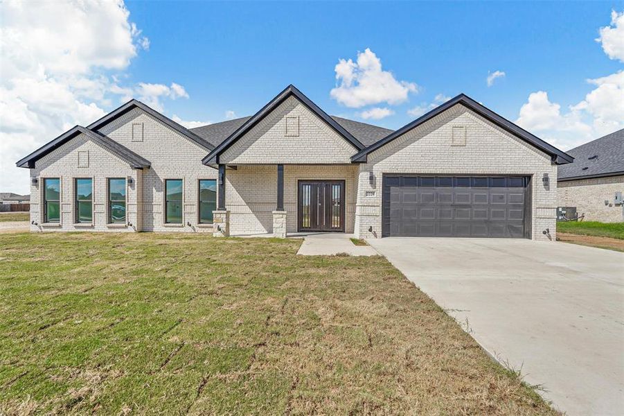 View of front of property with a front lawn, central AC unit, and a garage