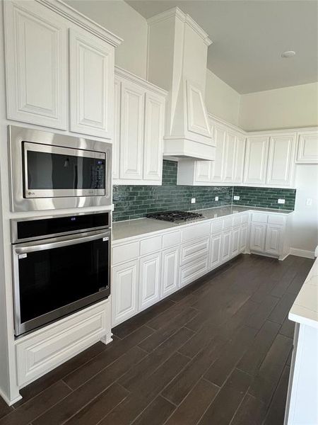 Kitchen featuring white cabinets, tasteful backsplash, appliances with stainless steel finishes, and dark wood finished floors