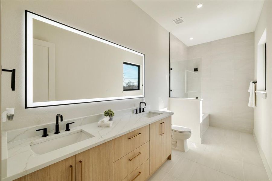 Bathroom featuring tiled shower, toilet, tile patterned flooring, and vanity